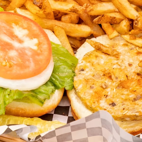 A Moody's Pub burger with lettuce, tomato, and onion, served with a side of golden fries.