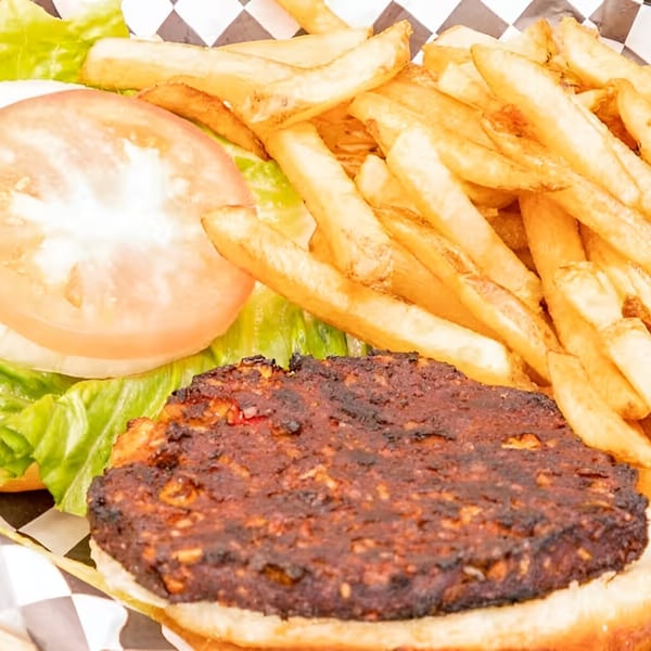 A close-up of a Moody's Pub burger with a dark patty, lettuce, tomato, and a side of fries.